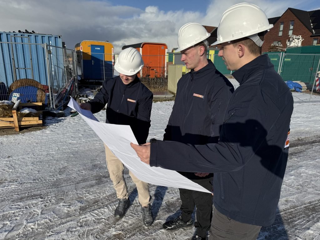Vakmensen van Bouwsector Nederland met witte helm bespreken een bouwtekening op een nieuwbouwterrein